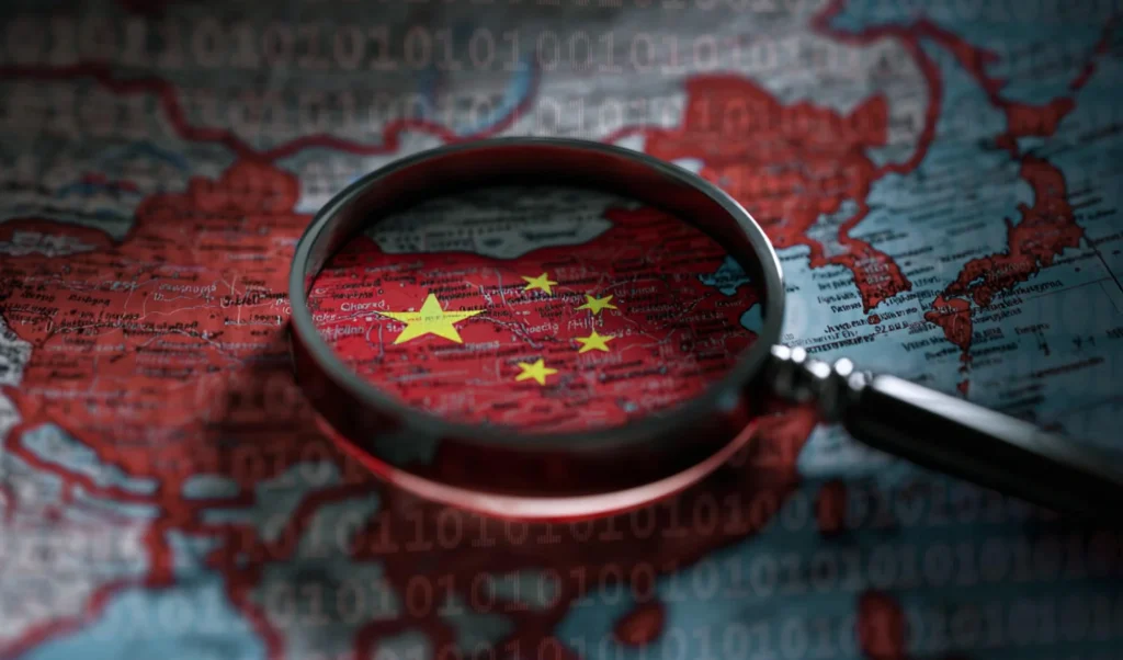 Magnifying glass over a map highlighting China with its yellow stars, against a backdrop of binary code.