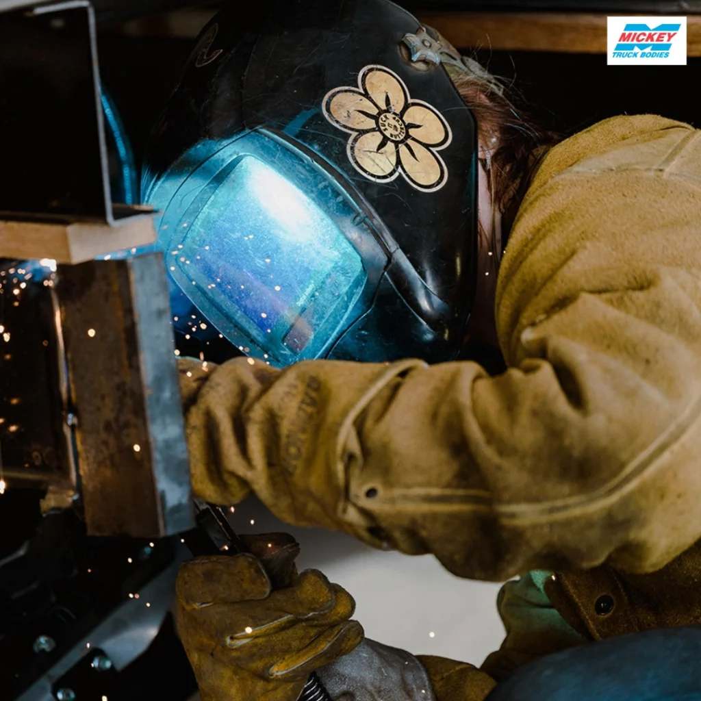 - GiaSpace: IT Support & Cybersecurity for Florida Businesses Welder in protective gear welding metal, blue visor glowing with sparks flying around.