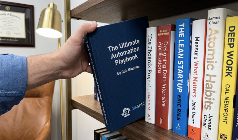 Hand reaching to pull a dark blue book titled 'The Ultimate Automation Playbook' from a bookshelf.
